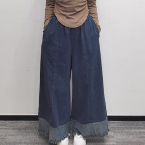 May include: Wide-leg denim pants with a frayed hem and a dark blue wash. The pants have a relaxed fit and a high waist.