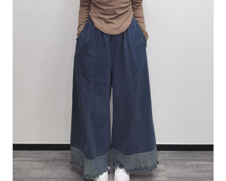 May include: Wide-leg denim pants with a frayed hem and a dark blue wash. The pants have a relaxed fit and a high waist.