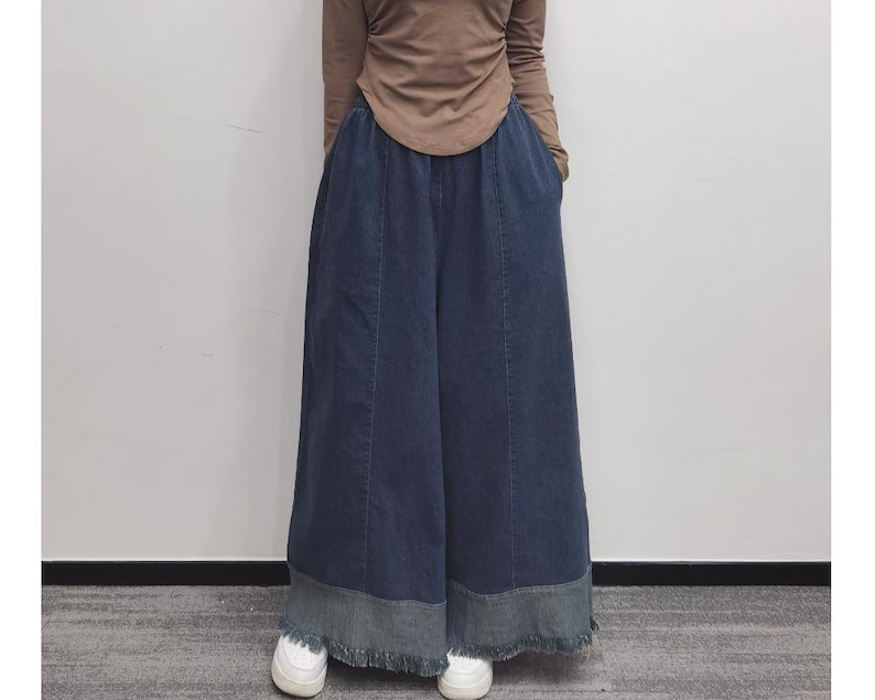 May include: Wide-leg denim pants with a frayed hem and a dark blue wash. The pants have a relaxed fit and are made of a soft, comfortable fabric.