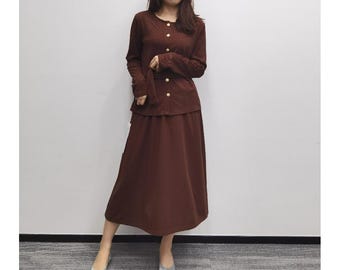 May include: A brown knitted cardigan with a button-up front and a matching brown skirt. The cardigan has a cable knit pattern and a belt.