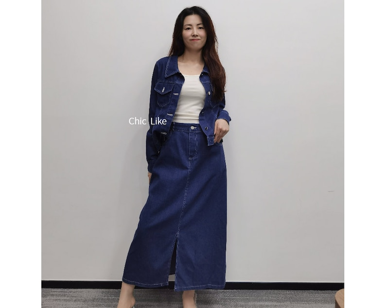 May include: A denim jacket and skirt set in a dark blue shade. The jacket has a classic collar and button closure. The skirt is A-line and has a front slit.