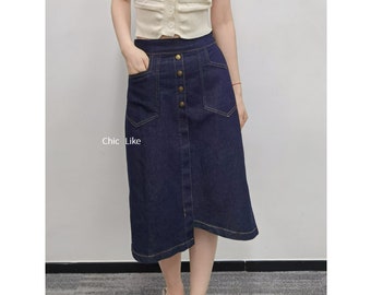 May include: A dark blue denim skirt with a button front and a single front pocket. The skirt has a slightly A-line shape and falls to just above the knee.