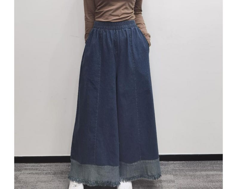 May include: Wide-leg denim pants with a frayed hem and a dark blue wash.