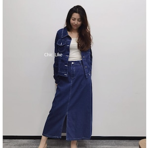 Op de afbeelding: Een vrouw draagt een donkerblauw denim jack en een bijpassende denim rok met een split aan de voorkant. De rok is knielengte en heeft een knoopsluiting op de taille.
