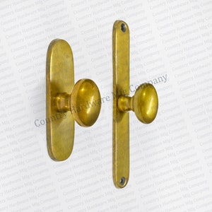 May include: A pair of antique brass door handles with a round knob and a rectangular plate. The handles are mounted on a white background.