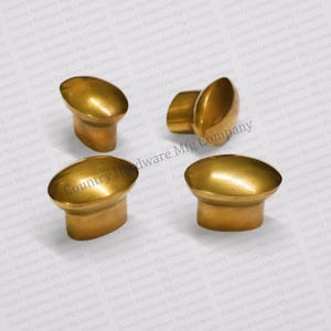 May include: Four gold-toned oval cabinet knobs with a raised edge. The knobs are on a white background.