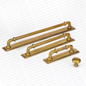 May include: Four antique brass cabinet pulls with a curved design and a knob. The pulls are arranged in descending size order, with the largest pull at the top and the smallest pull at the bottom. The knob is at the bottom right of the image.