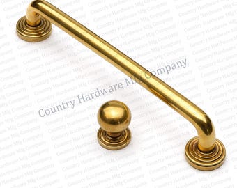 May include: A set of brass door hardware, comprising a long handle and a round knob. The handle is curved with decorative circular bases. The knob is spherical with a matching base. The hardware has a polished, golden finish.