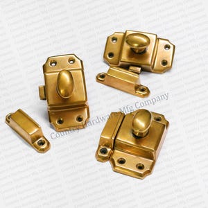 May include: Four antique brass cabinet door latches with oval knobs. The latches have a decorative design and are in excellent condition.