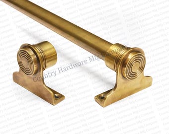 May include: A brass-colored curtain rod with decorative end pieces. The rod is cylindrical, and the end pieces have a spiral design. The hardware is designed for mounting to a wall. The image is of a new product.