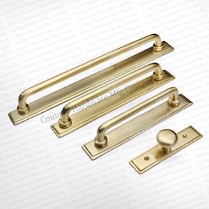 May include: A collection of gold-toned cabinet hardware, including handles and a knob. The handles vary in size, with curved grips and rectangular backplates. The hardware is likely for kitchen or furniture use.