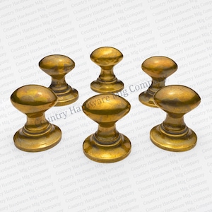 May include: Five antique brass door knobs with a rounded oval shape and a raised center. The knobs have a worn, aged finish.