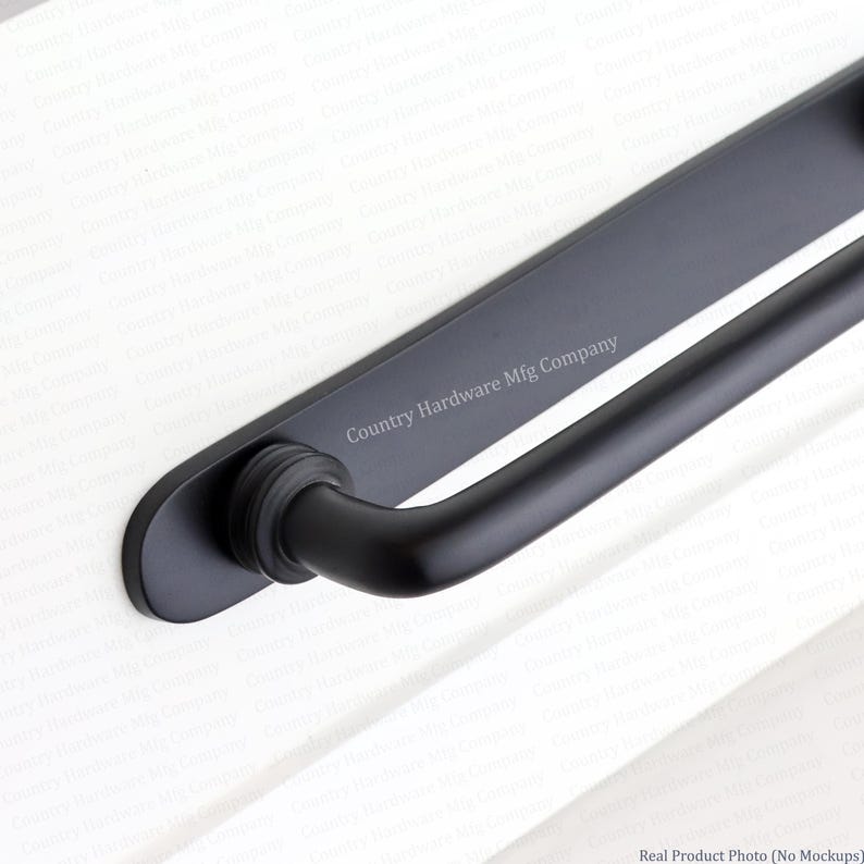 K&ouml;nnte beinhalten: Ein T&uuml;rgriff aus mattschwarzem Metall mit einer langen, flachen, rechteckigen R&uuml;ckplatte mit abgerundeten Enden und einem zylindrischen Griff. Der Text Country Hardware Mfg Company ist in Wei&szlig; auf der R&uuml;ckplatte aufgedruckt.