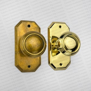 May include: Two antique door knobs with matching backplates. One knob has a bronze finish, the other is polished brass. Both have a round knob design and octagonal backplates. The text "Country Hardware Mfg Company" is visible.