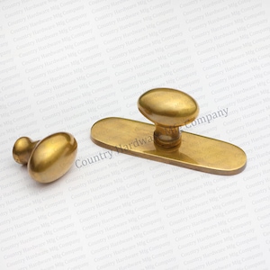 May include: A set of antique brass door hardware, including a long oval backplate with an oval knob and a matching oval door knob. The hardware has a warm, aged finish, suggesting vintage charm.