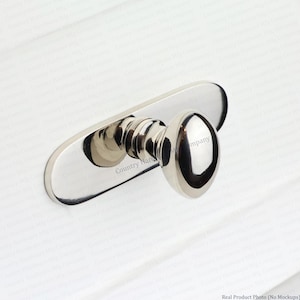 May include: A polished chrome cabinet knob featuring a smooth, rounded head and a tiered, cylindrical base attached to an elongated, oval-shaped backplate. The hardware has a reflective, metallic finish and includes the text Country Hardware Mfg Company.