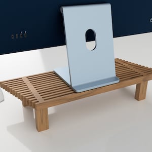 May include: A wooden stand with a slatted top, designed to elevate a computer monitor. The stand is made of light brown wood and has a simple, modern design.
