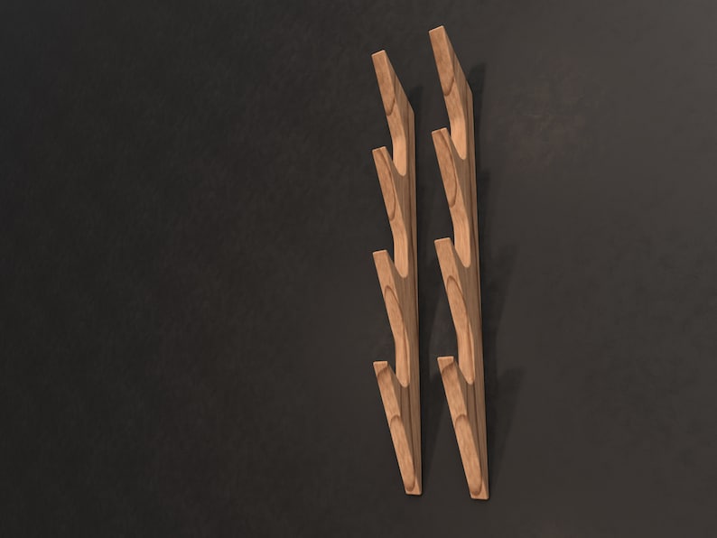 May include: Two wooden wall hooks with a branch-like design. Each hook has five curved branches that extend out from the main stem. The hooks are a light brown color and are mounted on a dark gray wall.