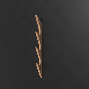 May include: A wooden wall-mounted coat rack with four hooks in a staggered design. The rack is made of light brown wood with a natural grain pattern.