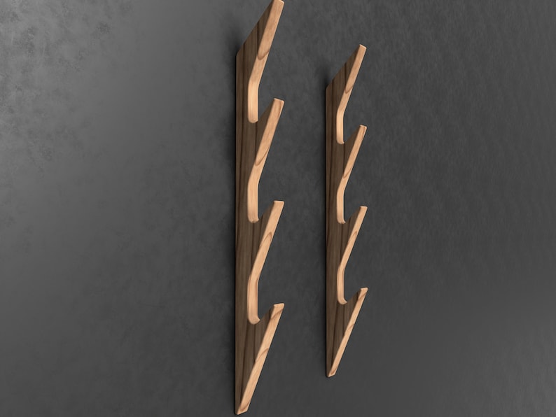 May include: Two wooden wall mounted coat racks with five hooks each. The racks are made of light brown wood with a darker brown wood grain. The hooks are curved and angled upwards.
