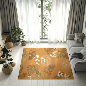 May include: An orange rectangular rug with a botanical leaf design. The rug displays large, stylized leaves in brown, green, and white against an orange backdrop. It is placed on a light wooden floor. The rug's design adds a natural element to the room.