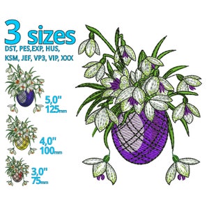 以下が含まれることがあります： 紫色の卵型の壺に白いスノードロップの花束が刺繍されたデザイン。デザインは3つのサイズで提供されています。5インチ、4インチ、3インチです。