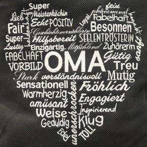 May include: A black heart-shaped canvas bag with white embroidery. The words "OMA" are in the center of the heart, surrounded by positive adjectives like "Super", "Fair", "Hilfsbereit", "Treu", "Fr&ouml;hlich", "Klug", and "TOLL".