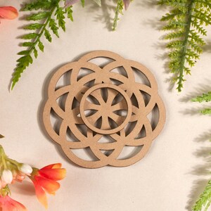 Könnte beinhalten: Ein Untersetzer aus Holz mit einem geometrischen Design, das einen Kreis in einem Kreis zeigt. Der Untersetzer ist braun und hat eine natürliche Holzoptik.