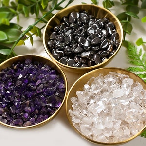 Könnte beinhalten: Drei kleine Schalen gefüllt mit verschiedenen Arten von Kristallen. Die Schalen sind golden und die Kristalle sind Amethyst, klarer Quarz und schwarzer Hämatit.