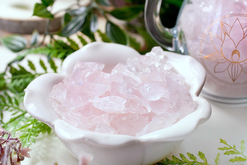 May include: A white ceramic bowl shaped like a flower with pink rose quartz crystals inside.
