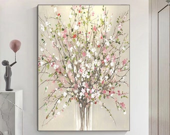 May include: An abstract floral painting featuring a bouquet of white and pink flowers with green leaves. The artwork is displayed in a clear vase against a neutral background. The painting is framed in a black border.
