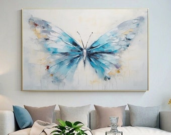 May include: A painting of a blue butterfly with watercolor-like brushstrokes on a white background. The butterfly is centered in the painting and has its wings spread wide. The painting is framed in a gold frame.