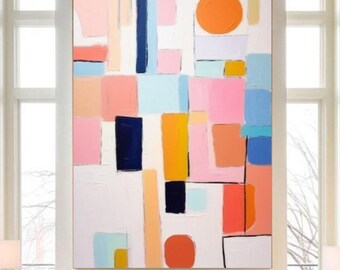 May include: Abstract artwork featuring a white backdrop with colourful geometric shapes. The painting includes blocks and lines in pink, orange, blue, yellow, and navy. An orange circle is in the upper right. The artwork is displayed above a white sofa.