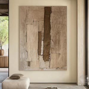 Può includere: Arte murale astratto con una tavolozza di colori neutri. L'opera d'arte presenta un design strutturato con toni beige, marrone e bianco sporco. Il pezzo incorniciato è esposto in un ambiente interno moderno, che completa lo schema di colori neutri della stanza.