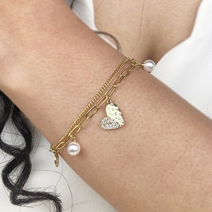 Peut inclure: Un bracelet en chaîne dorée avec un pendentif en forme de cœur et des accents de perles. Le pendentif en forme de cœur est décoré de petites pierres claires.