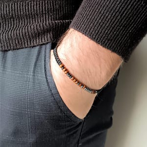 Peut inclure: Un bracelet avec des perles brunes et noires sur un cordon noir.