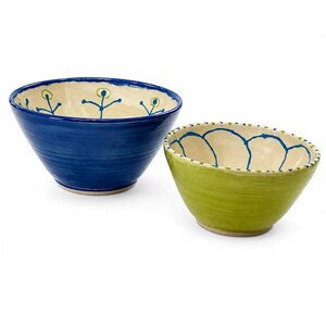 May include: Two ceramic bowls with a cream-colored interior and a hand-painted design. The larger bowl is deep blue with a blue floral pattern inside. The smaller bowl is lime green with a blue scalloped pattern and a dotted rim.