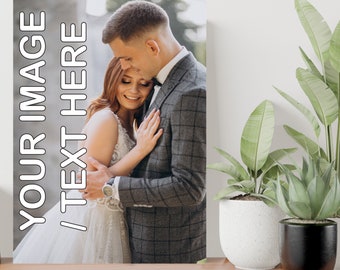 May include: A wedding photo of a couple embracing. The groom is wearing a gray checkered suit and the bride is wearing a white wedding dress. The photo is printed on a canvas.