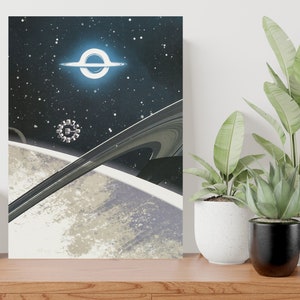 Può includere: Una stampa d'arte digitale che presenta un'astronave in orbita attorno a un pianeta con anelli, un buco nero e uno sfondo stellato.