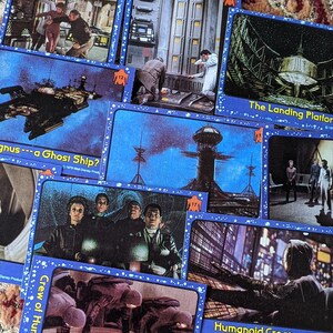 May include: A collection of trading cards featuring images from the 1979 film 'The Black Hole'. The cards feature images of the spaceship, the landing platform, the crew, and the air car. The cards are blue with white stars and have the title of the card printed in white.
