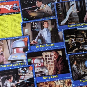 May include: A collection of trading cards featuring characters and scenes from the 1979 science fiction film "The Black Hole". The cards feature images of the characters, including Kate McCrae, V.I.N.CENT., Dr. Alex Durant, Harry Booth, and others. The cards also feature scenes from the film, such as the recreational break and the holographic projection.