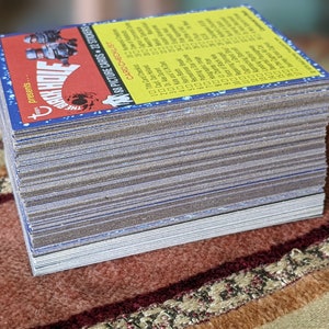May include: A stack of trading cards featuring a cartoon image of a monster with the text "The Black Hole presents..." and "188 Picture Cards + 22 Stickers". The cards are yellow with blue and red accents.