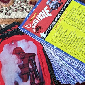 May include: A stack of 88 picture cards and 22 stickers from the 1979 film "The Black Hole". The cards feature a checklist of characters and scenes from the movie. The stickers are of various characters and objects from the film.