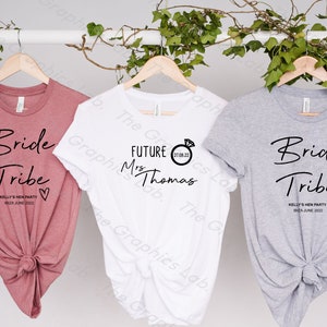 May include: Three t-shirts with text and a heart design. The pink shirt says "Bride Tribe" with the text "Kelly's Hen Party Ibiza June 2022". The white shirt says "Future Mrs Thomas" with a ring and the date "27.08.22". The grey shirt says "Bride Tribe" with the text "Kelly's Hen Party Ibiza June 2022".