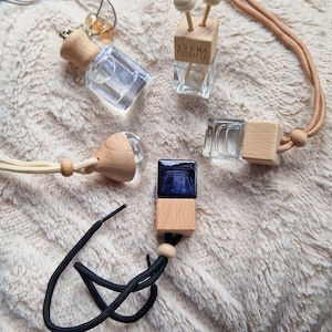 Peut inclure: Cinq différents diffuseurs de parfum pour voiture avec des parfums et des designs variés. Les diffuseurs sont en verre et en bois. Les diffuseurs sont suspendus à des cordes.