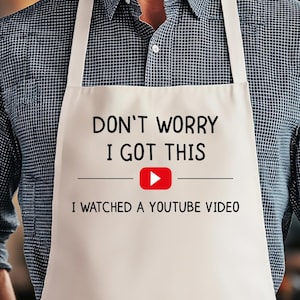 May include: A white apron with the text "DON'T WORRY I GOT THIS" above the phrase "I WATCHED A YOUTUBE VIDEO". The YouTube logo is red and white. The apron has white straps and is worn by a person.
