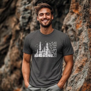 May include: A charcoal gray short-sleeve t-shirt featuring a white graphic print of a forest silhouette with birds and the text: of all the paths you take in life, make sure a few of them are dirt. The shirt has a crew neckline and a heathered texture.
