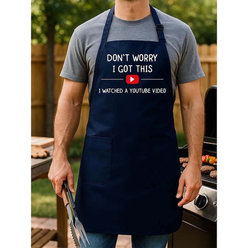 May include: Navy blue apron with the text "DON'T WORRY I GOT THIS" above a YouTube logo and the text "I WATCHED A YOUTUBE VIDEO". The apron has a front pocket and adjustable neck strap.