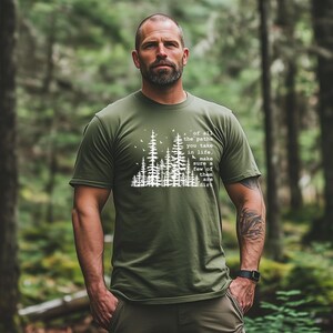 May include: An olive green short-sleeved t-shirt featuring a white graphic of a forest silhouette with birds and the text: of all the paths you take in life, make sure a few of them are dirt. The shirt has a crew neckline and a standard fit.