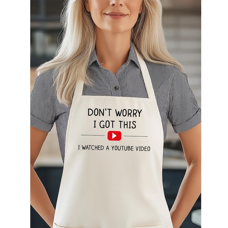 May include: Off-white apron with the text "DON'T WORRY I GOT THIS" above a red YouTube play button and the text "I WATCHED A YOUTUBE VIDEO". The apron has a neck loop and waist ties.
